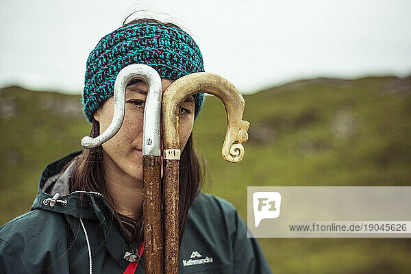 girl looks through hiking sticks in mountains