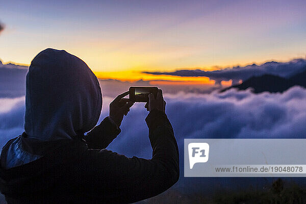Man takes photos with smartphone in mountains at sunrise