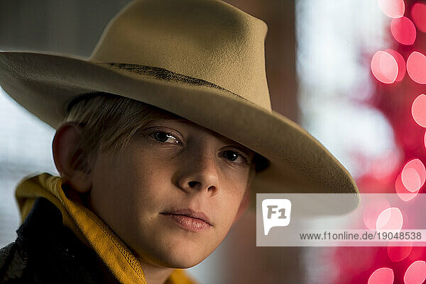 Portrait of boy wearing large hat with colorful lights in back
