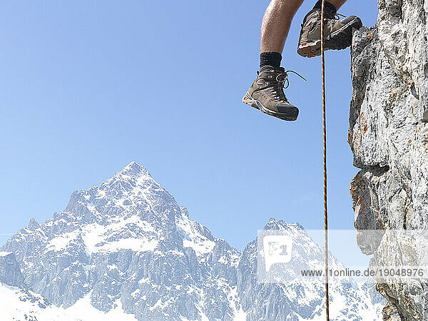 Mountaineer's legs ascend mountain ridge