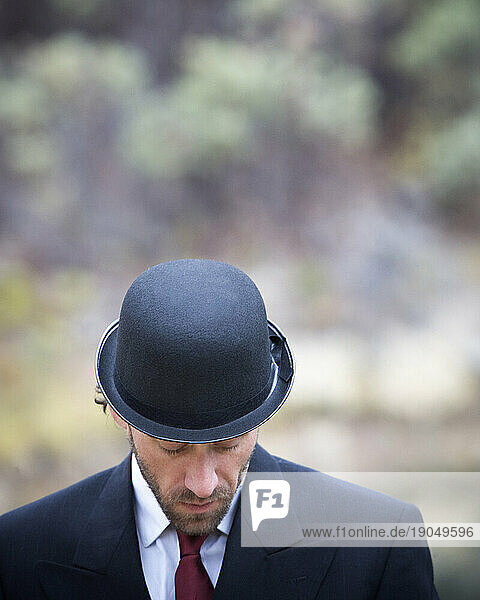 Portrait of a man with his head down wearing a bowler hat.