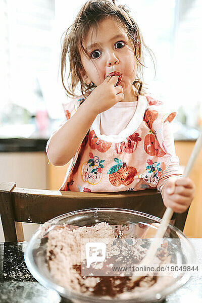 Toddler Girl tasting brownies in kitchen