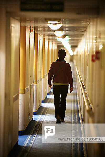 A woman walking down a hotel hallway.