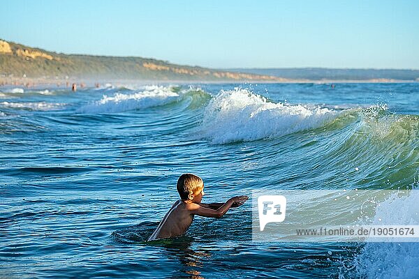 Junge hat Spaß genießt springt taucht in Ozean Meer Wellen des Atlantischen Ozeans. Strand Fonta da Telha  Costa da Caparica  Portugal  Europa