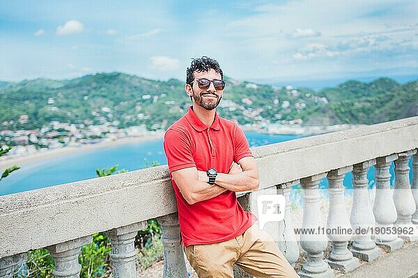 Gutaussehender Tourist mit Blick auf die Bucht von San Juan del Sur. Porträt eines lächelnden Touristen an einem Aussichtspunkt auf eine Bucht