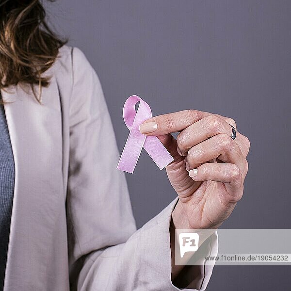 Rosa Schleife in der Hand einer Frau zur Unterstützung von Brustkrebs