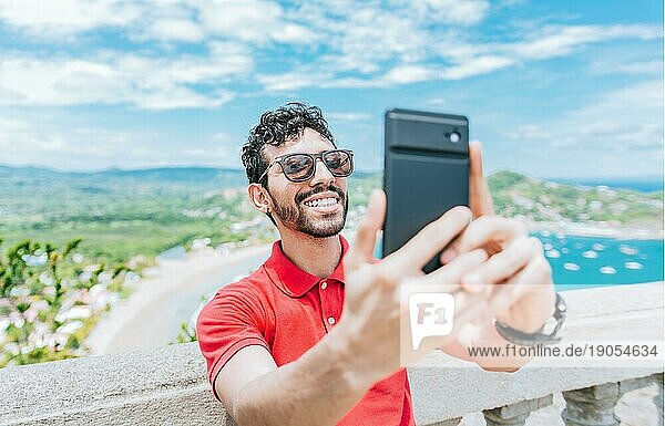 Glücklicher Tourist  der ein Selfie an einem Aussichtspunkt am Strand macht. Gutaussehender Mann  der ein Selfie am Aussichtspunkt von San Juan del Sur macht