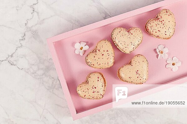 Süße herzförmige französische Macaronbonbons auf rosa Tablette