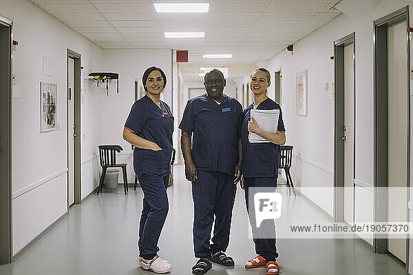 Porträt eines lächelnden männlichen und weiblichen medizinischen Personals  die zusammen auf dem Flur eines Krankenhauses stehen