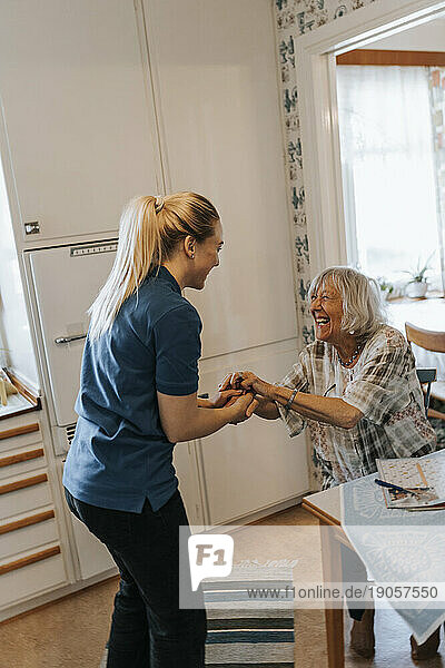 Seitenansicht einer weiblichen Pflegekraft  die sich mit einer älteren Frau zu Hause unterhält