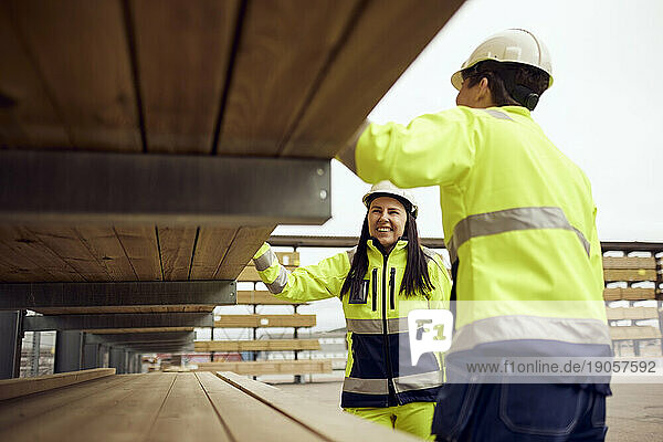 Eine lächelnde Arbeiterin prüft mit einem Kollegen in der Industrie die Bretter