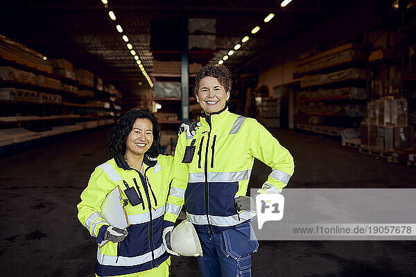 Porträt einer lächelnden multirassischen Mitarbeiterin in Arbeitskleidung  die in einer Fabrik steht