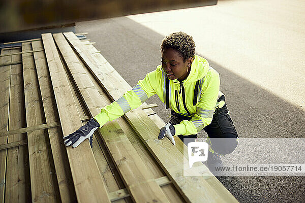 Lächelnde Arbeiterin beim Verteilen von Brettern in der Holzindustrie