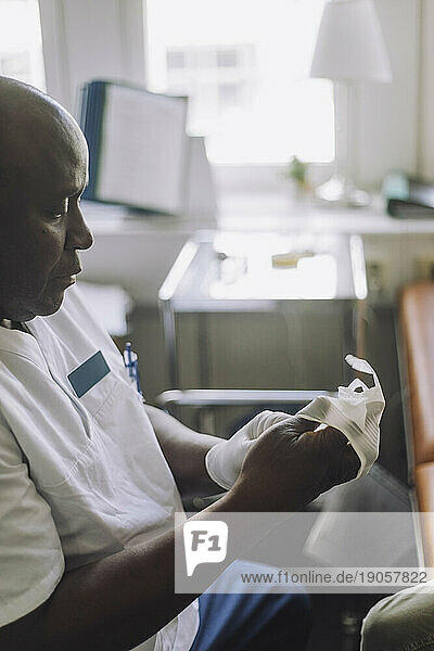 Männlicher Mitarbeiter im Gesundheitswesen trägt Handschuhe in einer Klinik