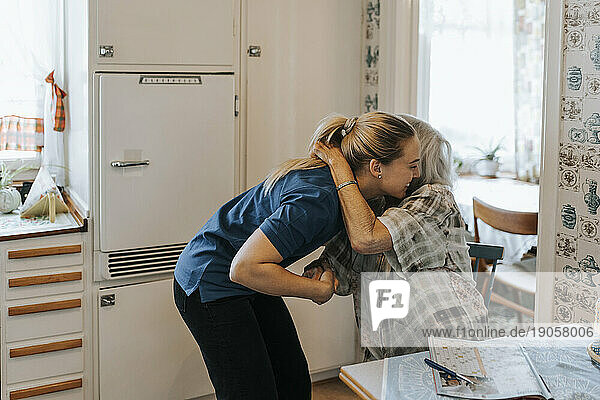 Ältere Frau umarmt weibliche Pflegekraft zu Hause