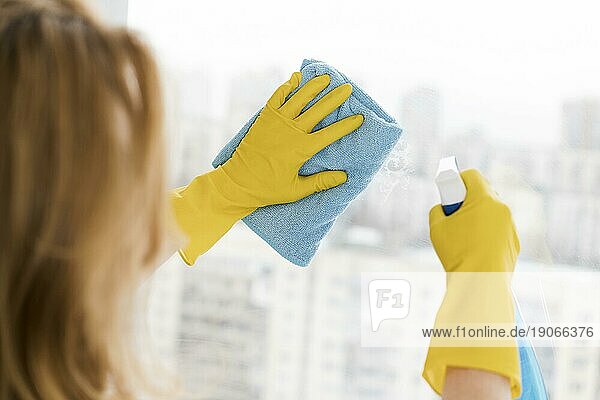 Frau putzt Fenster mit Lappen