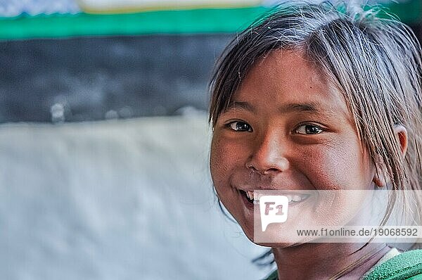 Dolpo  Nepal  ca. Mai 2012: Junges braunhaariges Mädchen lächelt freundlich in die Fotokamera mit braunen glitzernden Augen in Dolpo  Nepal. Dokumentarischer Leitartikel  Asien