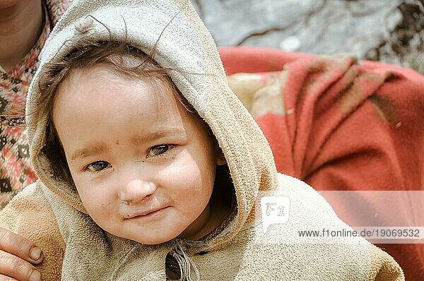 Dolpo  Nepal  ca. Juni 2012: Kleines braunhaariges Kind in braunem Pullover blickt neugierig mit funkelnden braunen Augen in die Fotokamera in den schönen Bergen von Dolpo  Nepal. Dokumentarischer Leitartikel  Asien