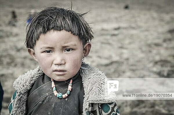 Dolpo  Nepal  ca. Juni 2012: Kleines einheimisches Mädchen mit kurzen schwarzen Haaren  bekleidet mit grauem Hemd und warmer Jacke  mit großen schwarzen Augen in Dolpo  Nepal. Dokumentarischer Leitartikel  Asien