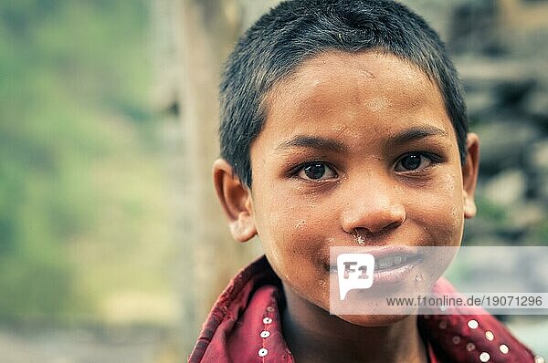 Beni  Nepal  ca. Mai 2012: Junger einheimischer Junge mit großen braunen Augen und weißem Schmutz im Gesicht lächelt und schaut auf in Beni  Nepal. Dokumentarischer Leitartikel  Asien