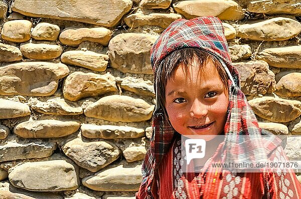 Dolpo  Nepal  ca. Juni 2012: Kleiner braunhaariger Junge mit rotkarierter Kopfbedeckung und rotem Hemd mit schönen braunen Augen in Dolpo  Nepal. Dokumentarischer Leitartikel  Asien