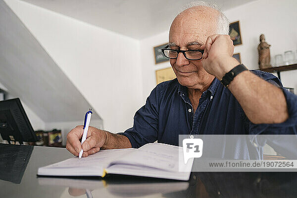 Smiling cafe owner wearing eyeglasses writing in diary