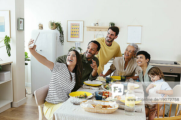 Smiling family taking selfie sitting at dining table at kitchen
