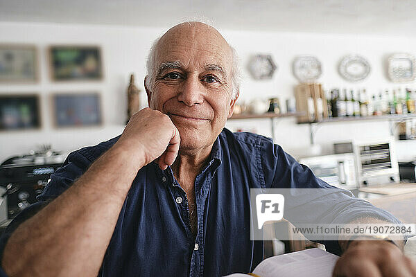 Smiling coffee shop owner sitting in cafe