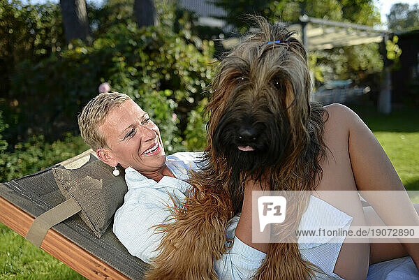 Portrait of happy woman cuddling with her dog in the garden