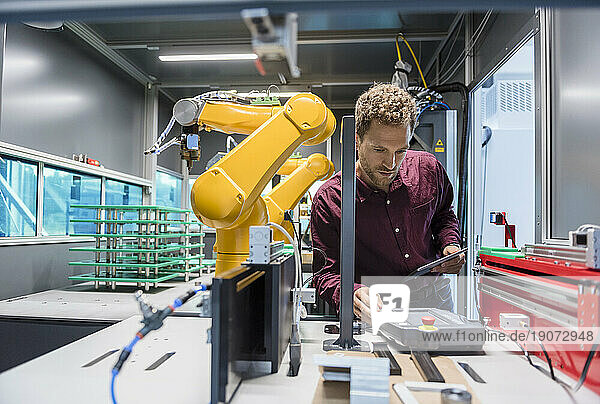 Businessman checking industrial robot in high tech company