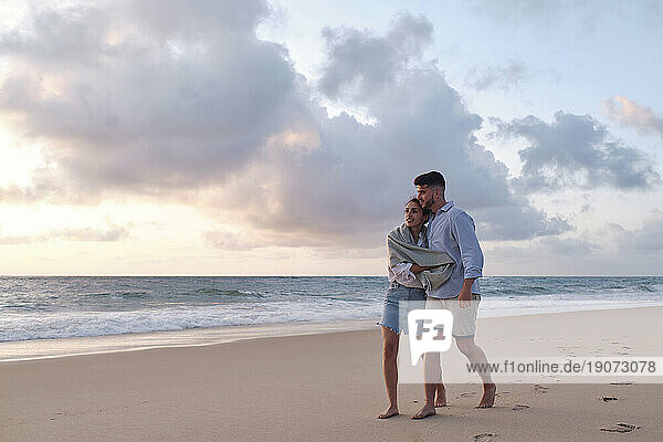 Man and woman spending leisure time walking on sand at beach