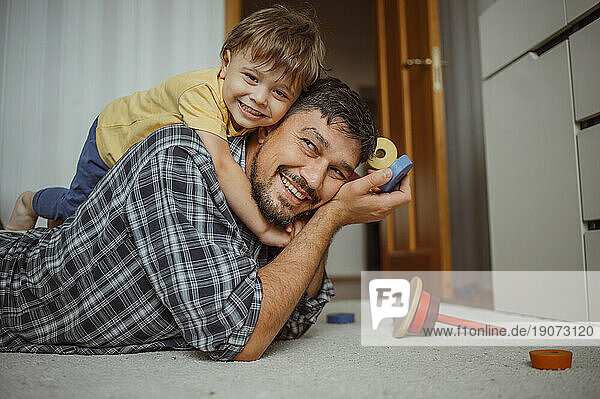Smiling father and son playing with toys at home