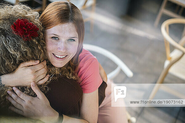 Smiling woman embracing friend at cafe