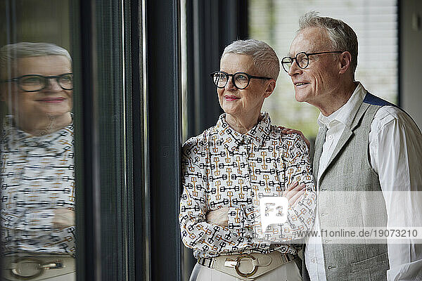 Senior couple at home looking out of window
