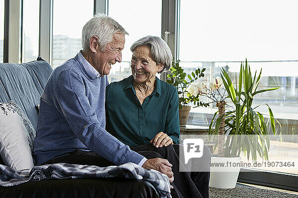 Laughing senior couple sitting together on couch