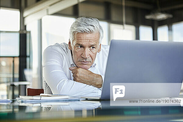 Businessman sitting at desk  trying to solve a problem