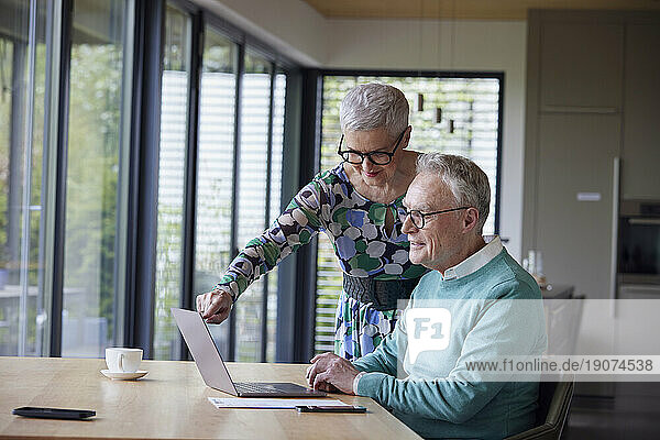 Senior couple using laptop at table at home