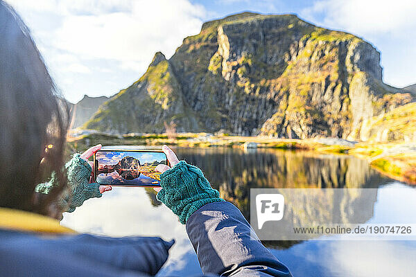 Personal perspective of woman photographing mountains in autumn with smartphone,  A i Lofoten,  Moskenes,  Lofoten Islands,  Nordland,  Norway,  Scandinavia,  Europe