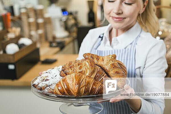 Close up lächelnde junge Frau riecht frisch gebackenen Croissants Kuchen stehen