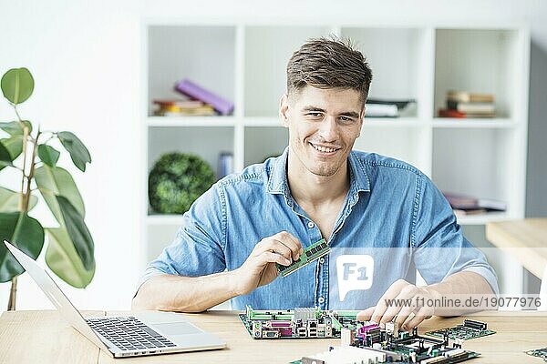 Lächelnder junger männlicher IT Techniker mit Hardware Ausrüstung