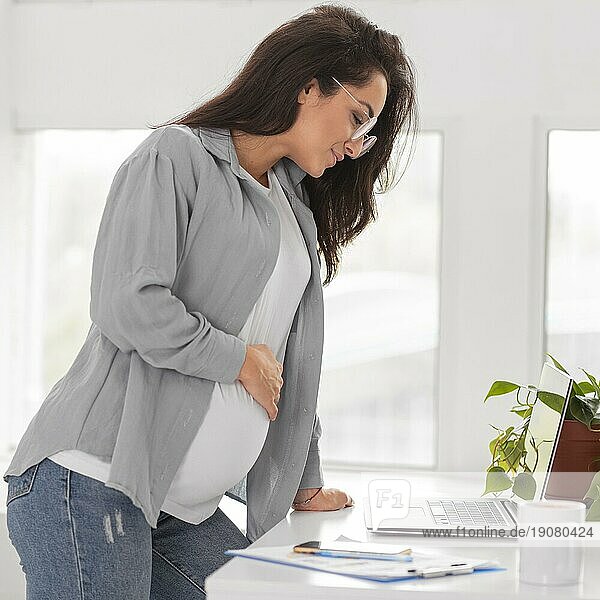 Seitenansicht schwangere Frau arbeitet Laptop zu Hause