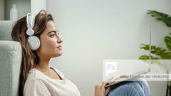 Seitenansicht Frau mit Kopfhörern am Laptop