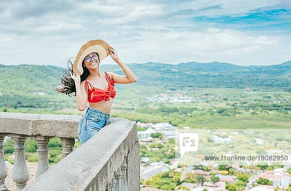 Glückliche Urlauberin mit Hut auf einem Aussichtspunkt. Porträt der schönen Tourist Mädchen in einem Aussichtspunkt  Reisen und Tourismus Förderung Konzept