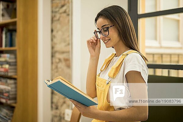 Attraktive junge Frau  die ein Buch in der Bibliothek liest
