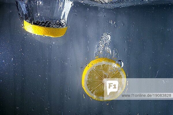 Zwei Scheiben Zitrone  die ins Wasser fallen