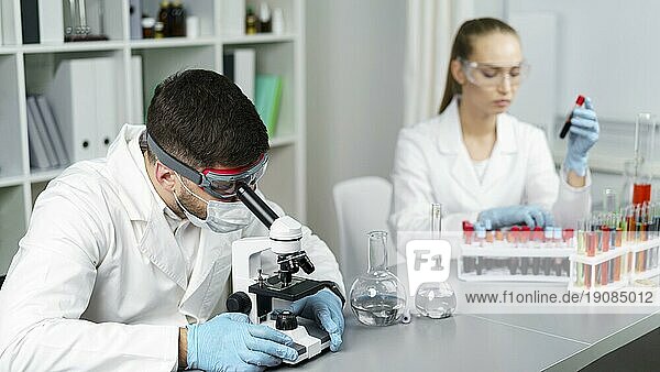 Weibliche Forscherin männlicher Kollege Labor mit Reagenzgläsern Schutzbrille