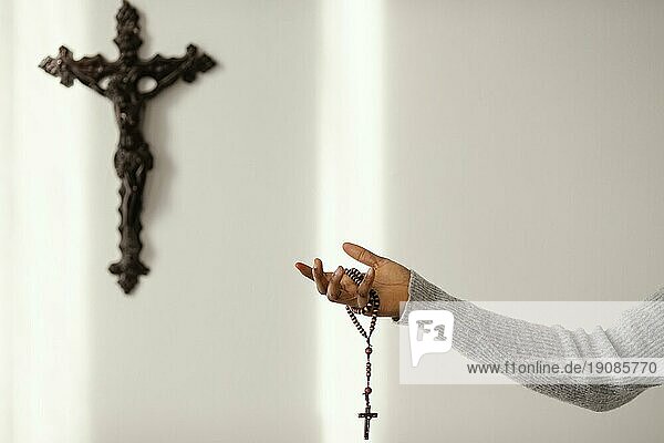 Religiöse Frau betet mit Rosenkranzperlen zu Hause