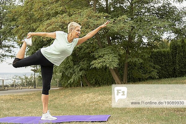 Seitenansicht ältere Frau übt Yoga im Freien Park