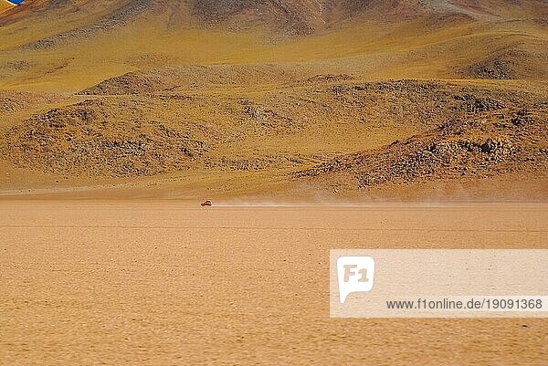 Foto eines Autos  das in der Ferne durch eine Sandwüste in Bolivien fährt