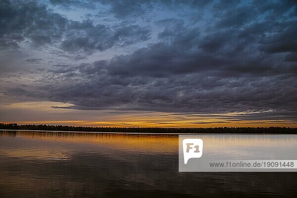 Foto von bewölktem Himmel über einem See mit dunklem Wald in der Ferne in Ranua in Finnland